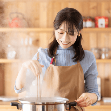お鍋で料理をする若い女性